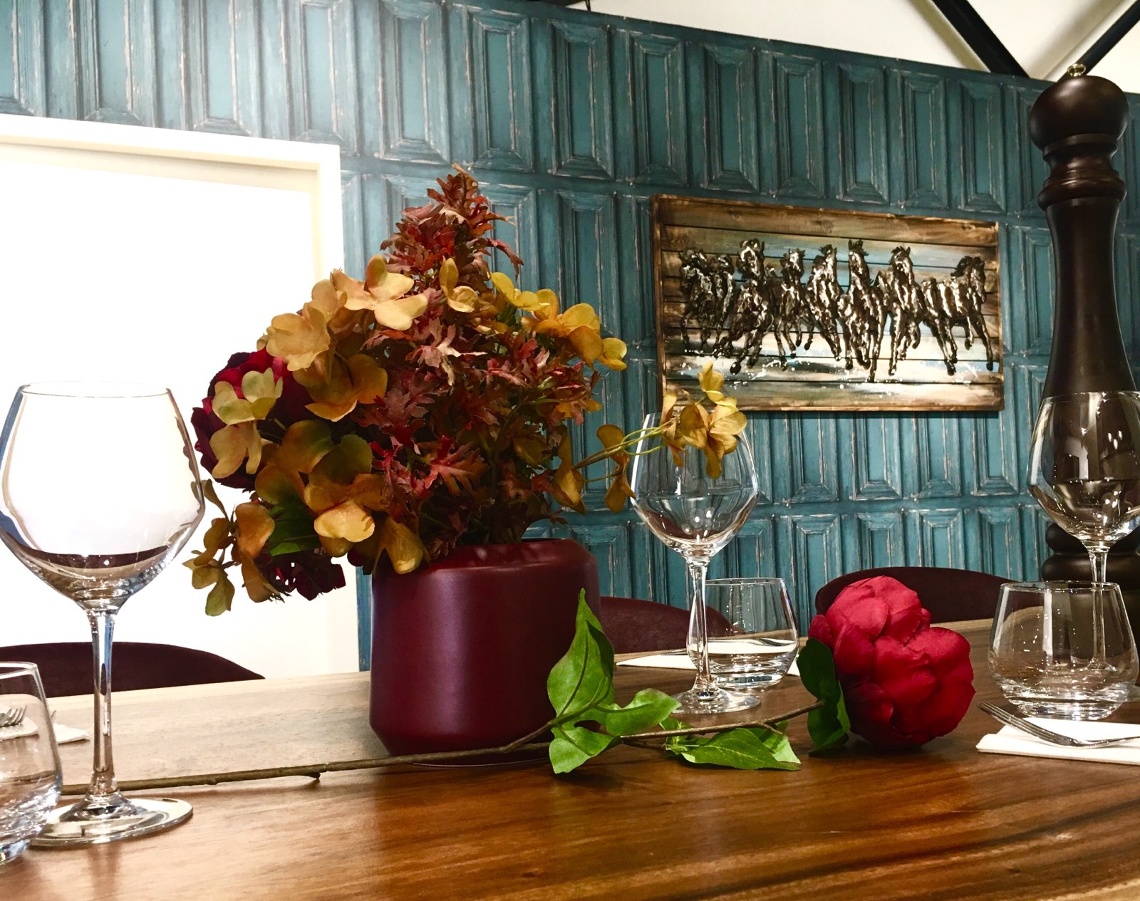 Table dressée et décoration florale au restaurant La Pôse Bistrot Aigues-Mortes — salle intimiste avec boiseries patinées et tableau chevaux camarguais